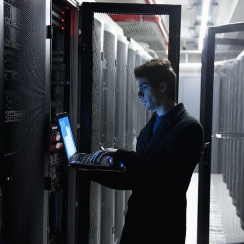 An IT technician programming computer equipment in a server room